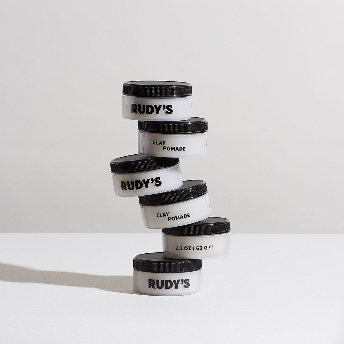 Image of 6 unevenly stacked Clay Pomades