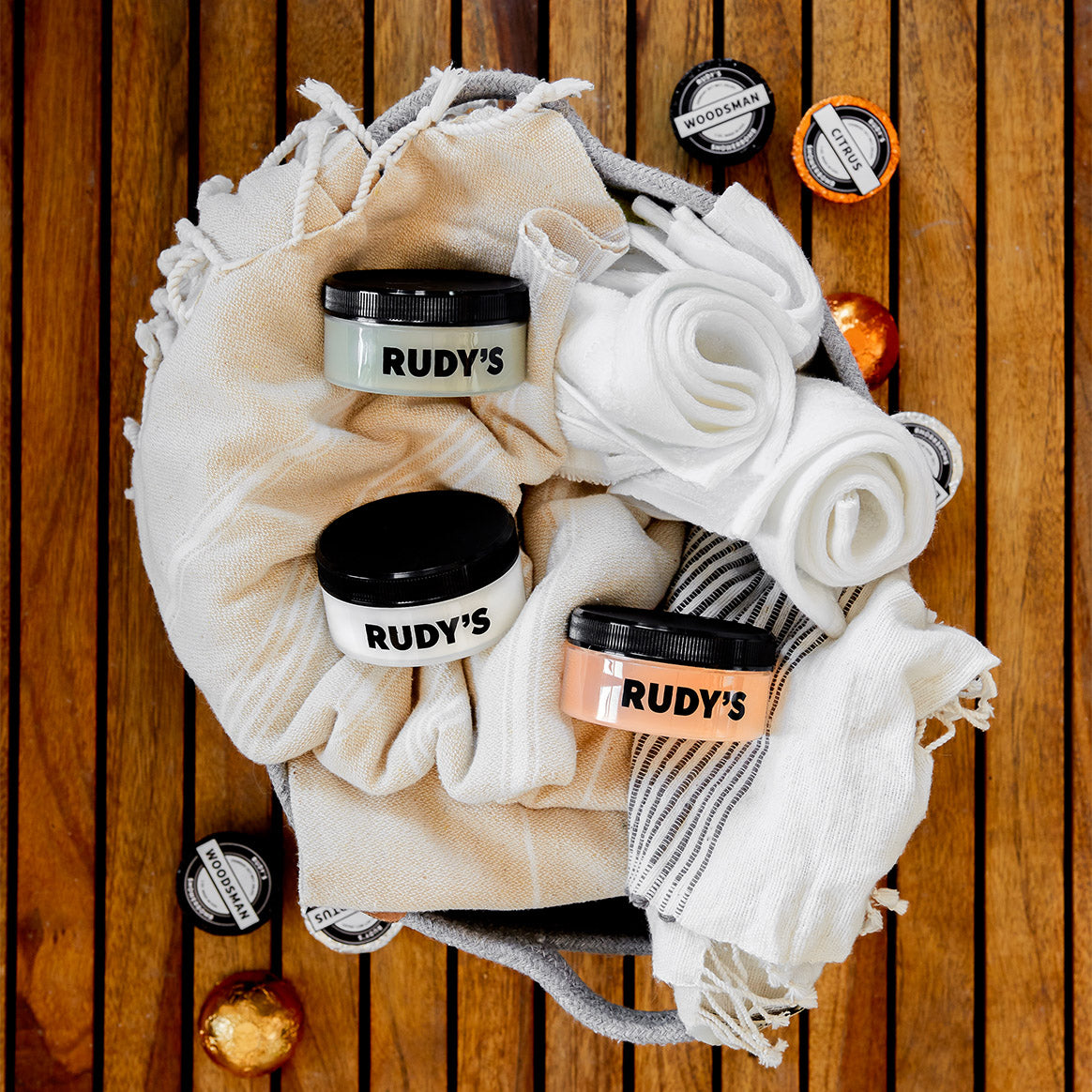 Image of Clay, Matte, and Shine Pomades in basket with towels and shower bombs