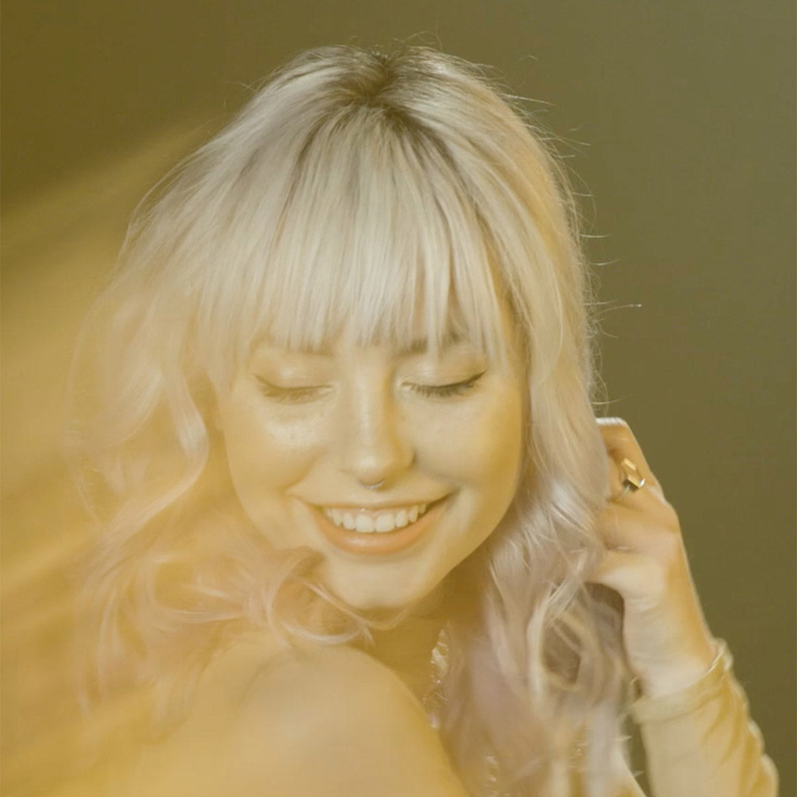 Woman with wavy blonde hair and straight bangs styled with Clay Pomade